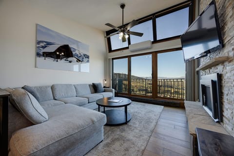 Unwind in your stylish living room with panoramic windows framing stunning views, cozy sectional seating, and modern fireplace for perfect evenings.