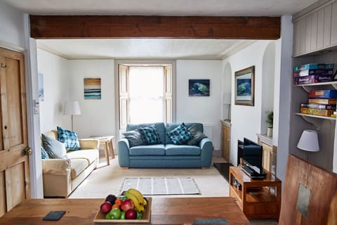 Sunny open-plan living with two sofas, games shelf and coastal art throughout.