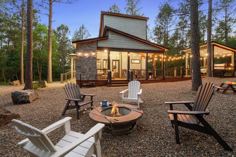 Modern cabin nestled among towering pines with outdoor fire pit, string lights, and spacious deck for memorable forest evenings.
