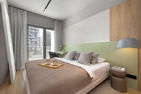 A bright bedroom with a neatly made bed, soft lighting, and large windows bringing in natural light.