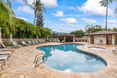 A pristine pool surrounded by swaying palms and lush tropical greenery, with a relaxing hot tub just steps away—perfect for unwinding under the Hawaiian sun.
