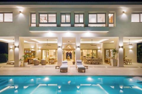 Night view of the villa with covered terrace, outdoor dining, and illuminated po