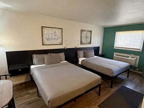 Two queen beds with nautical artwork, ship`s lantern sconces, and a bold green accent wall