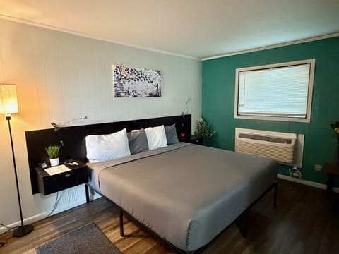 The Garden Room`s sage-green accent wall, queen bed, and natural light — a peaceful boutique stay just minutes from Cedar Point and the Lake Erie islands.