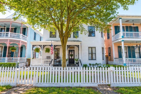 Charming Galveston historic home exterior featuring white picket fence, shaded front yard, and classic coastal architecture on Avenue M.