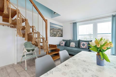 A bright living area with a staircase leading upstairs, a cozy sofa, and large windows letting in plenty of natural light.