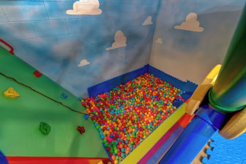 Dive into the fun! Our indoor play area features a massive ball pit and a rock-climbing wall under a sky-themed mural. It’s the ultimate spot for high-energy adventures and endless kid-friendly excitement!