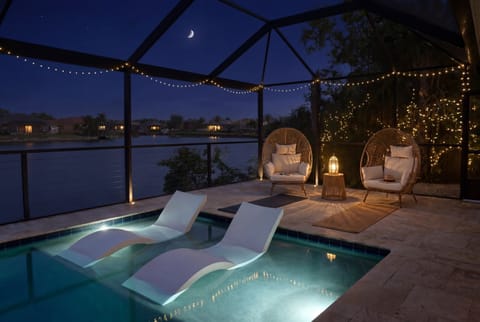 Sleek loungers float right in the pool under a starlit, screened-in lanai.
