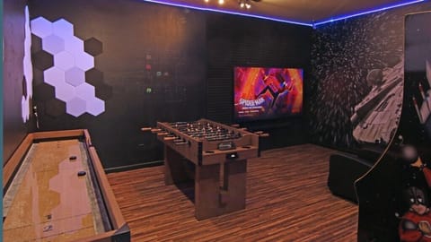 Entertainment room with foosball, shuffleboard, and large screen for movie nights.