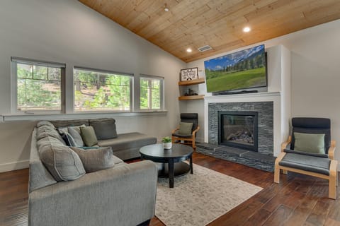 Cozy living area w/ soaring wood ceilings, stone fireplace & oversized windows bringing in natural light