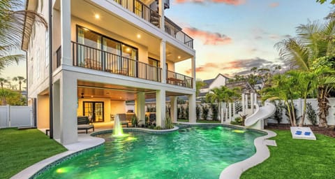 Lido Palms backyard at sunset with the pool, spa, and waterslide all softly lit for evening swims.