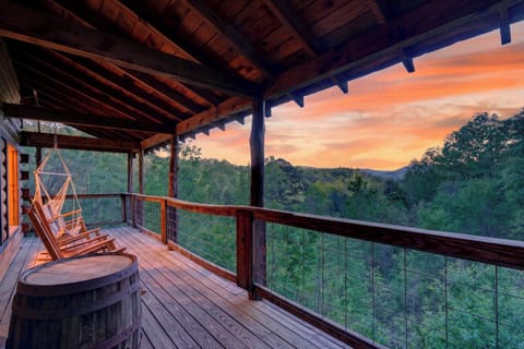 Expansive covered deck with rocking chairs, a hanging swing, and sweeping Smoky Mountain sunset views.