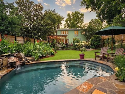 A lush private backyard with a pool, tropical plants, and Adirondack chairs is a true Nashville oasis.