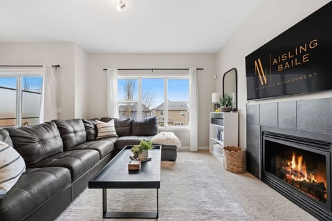 Main floor living room with an electric fireplace, 60` Smart TV, and a cozy sectional.