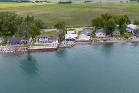 Private Waterfront Patio: Step out onto the expansive wooden deck to breathe in the fresh lake air or enjoy a morning coffee right at the water`s edge.  Backyard Gathering Spot: A vibrant seating area with colorful Adirondack chairs surrounds a fire pit, 