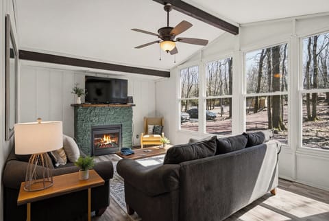 Warm and inviting living room featuring a stone fireplace and large windows.