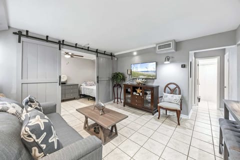 Cozy living area with sliding barn doors leading to the bedroom and a wall-mounted TV for entertainment.
