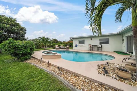 Private backyard with a curved pool and seating area surrounded by lush greenery.
