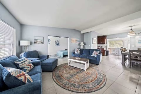 Spacious living area with comfortable blue seating and open access to the dining and kitchen spaces.