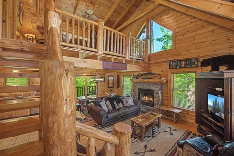 Relax in this stunning log cabin living room where rustic charm meets modern comfort, with soaring ceilings and a cozy fireplace.
