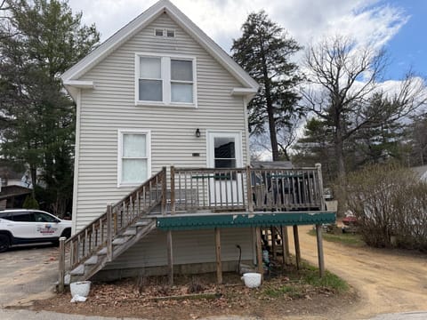 Charming two-story home featuring a welcoming elevated deck perfect for morning coffee and evening relaxation in a peaceful wooded setting.