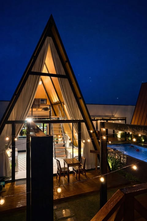Vista noturna da cabana industrial com iluminação aconchegante e ambiente integrado, criando uma atmosfera perfeita para momentos especiais.