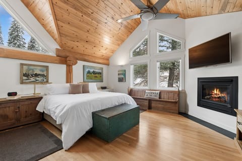 Cozy up in your mountain bedroom with crackling fireplace, soaring wood ceilings, and peaceful forest views through expansive windows.