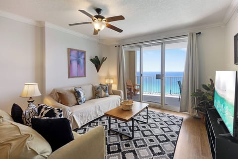 Relax in your bright living space with stunning ocean views through floor-to-ceiling windows, complete with cozy seating and modern amenities.