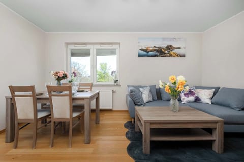 A dining area with a wooden table and chairs positioned near a window, offering a pleasant spot for meals. The room is filled with daylight and decorated with simple, tasteful accents.