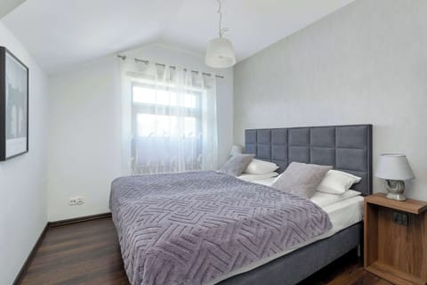 A bright bedroom with a neatly made bed and soft natural light coming through a window. The room has simple decor and a calm, minimalist feel.