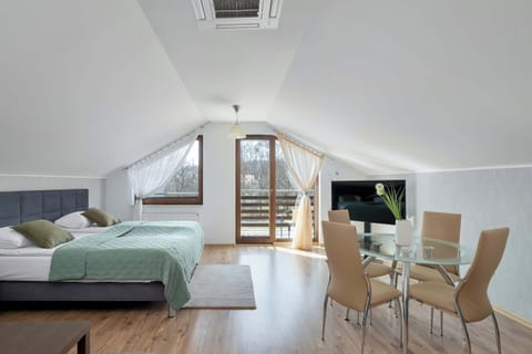 A bright open-plan living area combining a dining space and lounge with a modern, minimalist design. Large windows bring in plenty of natural light and create a spacious feel.