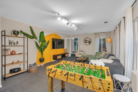 Unwind in your vibrant living space with cozy seating, foosball fun, and relaxed vibes.