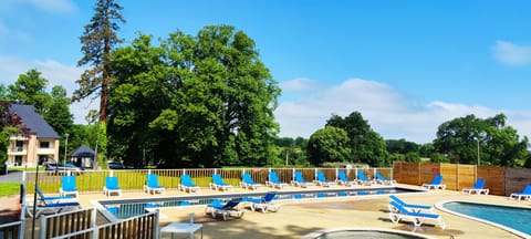 Sun loungers line the poolside, backed by the tall trees of the surrounding park.