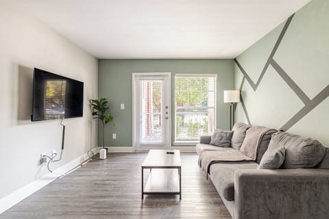 Bright modern living room with sectional, TV, and stylish accent wall