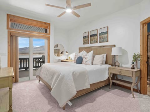 Bright and serene bedroom with a plush bed and direct access to a private balcony with lake and mountain views.