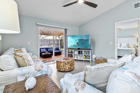 Bright & airy living room with a large smart TV and sliding glass doors that lead to screened-in patio