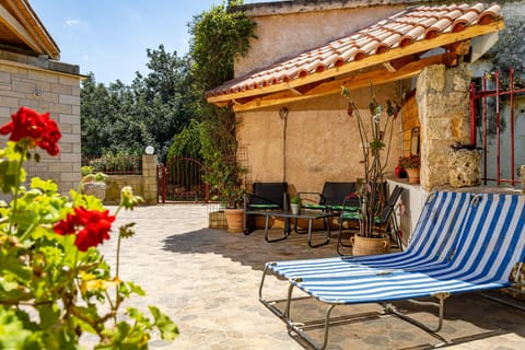 Sunny stone patio with loungers and blooming flowers