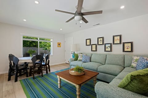 Unwind in your bright, open living space featuring a cozy sectional sofa and dining area with garden views.