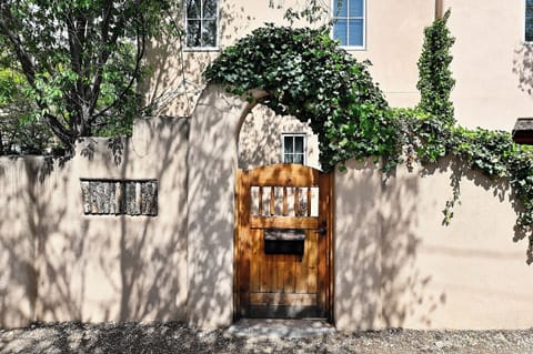 Charming entrance with ivy-covered archway and rustic wooden gate welcomes guests to this peaceful adobe-style property.