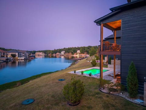 Tranquil twilight setting featuring glowing waters, comfortable outdoor living spaces, and sweeping panoramic shoreline views.