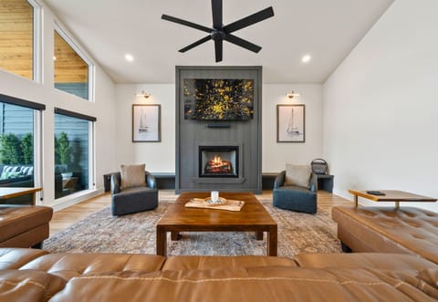 Open-concept living space with a cozy fireplace, wall-mounted TV, and plush seating.