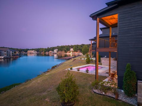 Twilight exterior shot highlighting the modern architectural design, ambient indoor lighting, and poolside deck.