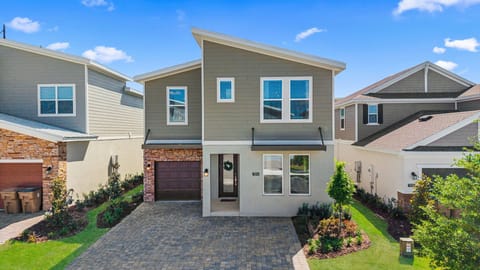 Contemporary exterior with paver driveway, private garage, and lush landscaping-your stylish Reunion home base awaits!