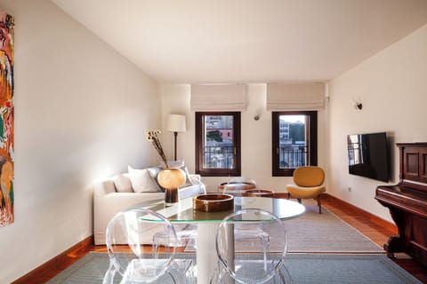 The living room features a 55” Smart TV, a dining table, and a piano