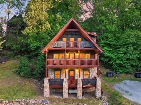 Rustic multi‑story cabin glowing warmly among the trees, with stacked balconies overlooking a peaceful forest setting.