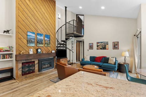 Relax in this inviting living room with soaring ceilings, cozy fireplace, and stylish spiral stairs leading to your private loft. The open layout and warm wood tones create a perfect home base.