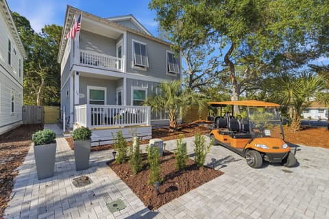 Charming two-story coastal home with mature shade trees and convenient golf cart for easy neighborhood exploration.