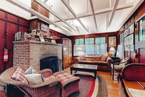 Sink into cozy wicker chairs beside your wood-burning brick fireplace — rich wood paneling and vaulted beams set the tone for a true redwood retreat evening.