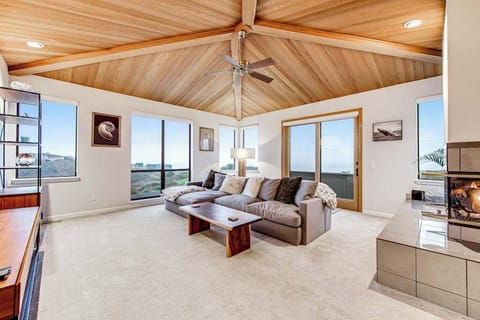 Gather beneath soaring vaulted wood ceilings in your main living room — panoramic windows fill the space with golden coastal light all day long