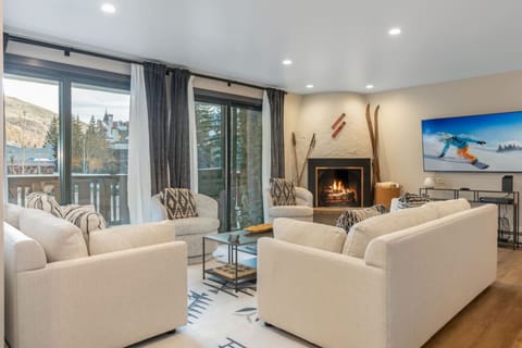 Elegant living room with plush seating, smart TV, fireplace, and views of Vail Village